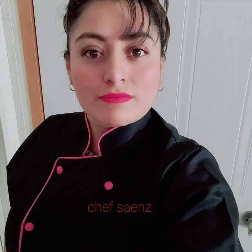 Portrait of Chef Saenz, founder and head chef of Pupusería Patty’s, wearing a black chef coat with pink trim